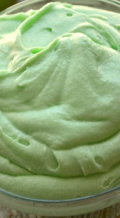 a bowl filled with green frosting on top of a table