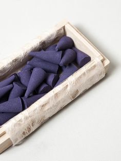 a wooden box filled with purple pieces of fabric sitting on top of a white table