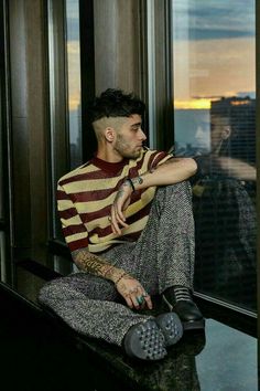 a man sitting on top of a window sill