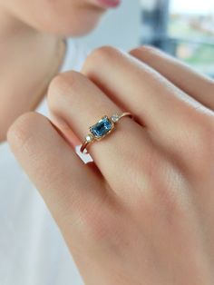 a woman's hand with a ring on it and a blue stone in the middle