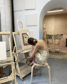 a woman is sitting on a chair in an art studio