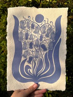 a hand holding up a blue and white paper with an image of flowers on it