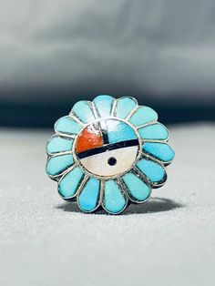 "MAKE US AN OFFER BY CLICKING THE \"MESSAGE SELLER\" Button- Up for sale is this marvelous vintage Zuni silver ring having an inlay sunface of turquoise, coral, jet and mother of pearl surrounded by inlay turquoise teardrops with a scalloped silver border and a handcarved solid silver band! Absolutely Captivating! The ring face measures around 7/8\" x 7/8\". The ring size is around 8. Sterling silver. Sturdy 5 grams. Cir mid century. Make Us an Offer- Due to the high demand of our items, many pi Blue Turquoise Ring With Inlay, Collectible Round Turquoise Ring, Collectible Blue Turquoise Inlay Ring, Handmade Blue Turquoise Ring For Collectors, Vintage Blue Cabochon Ring, Vintage Blue Turquoise Cabochon Ring, Vintage Blue Cabochon Turquoise Ring, Vintage Turquoise Ring Gift, Antique Handmade Turquoise Blue Ring