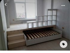 an empty room with stairs leading up to the window and a bed in the middle