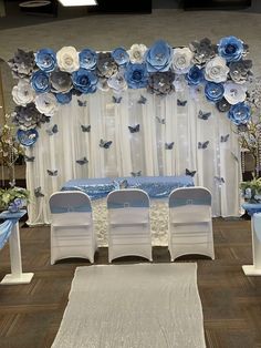 a blue and white wedding set up with flowers on the wall, butterfly decorations around the table