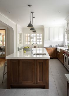 a large kitchen with an island in the middle and two pendant lights hanging from the ceiling