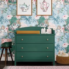 a baby's room with floral wallpaper and green dresser in the foreground