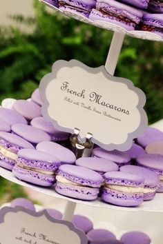 purple macaroons are stacked on top of each other with a sign that says french macaroons