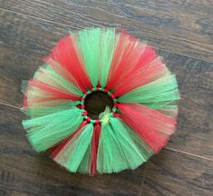 a red and green tulle wreath on a wooden floor