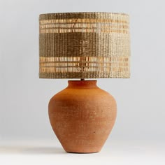 an orange vase with a woven lamp shade on the top is sitting in front of a white background