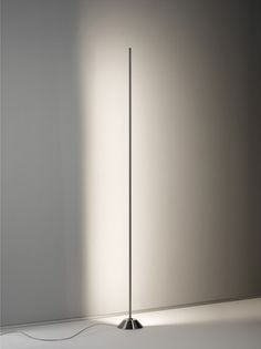 the floor lamp is lit up in an empty room with light coming from behind it