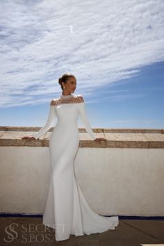 a woman in a white dress standing on a ledge