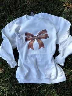 Trendy Football Bow Crew Neck! Perfect go to piece for this football season! White Sweatshirt Fan Gear For Fall, White Fan Gear Sweatshirt For Fall, White Sweatshirt For Fall Fan Gear, White Sports Fan Sweatshirt For Fall, White Sports Fan Top For Fall, White Tops For Fall Sports Fans, White Sweatshirt For Football Season Game Day, White College Sweatshirt For Football Season, Varsity White Sweatshirt For Football Season