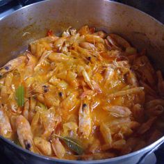 a pan filled with pasta and shrimp on top of a stove