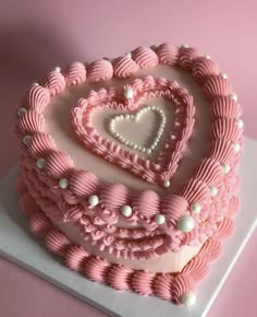 a heart shaped cake with pink icing and white decorations