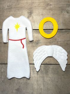 an infant's dress and accessories are laid out on a wooden surface, including a yellow ring