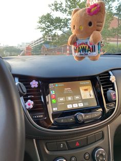 a hello kitty stuffed animal hanging from the dashboard of a car with an ipod in front of it