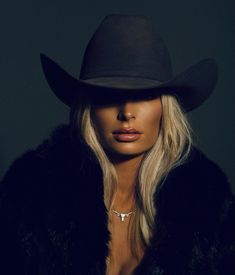 a woman with blonde hair wearing a black hat and fur coat, posing for the camera