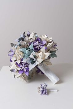 a bridal bouquet with purple and white paper flowers on the side, next to a pair of scissors