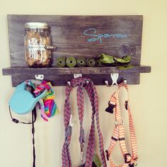 a wooden shelf with several different leashes hanging from it's sides and two mason jars on the wall