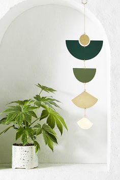 a potted plant sitting on top of a white shelf next to a wall hanging