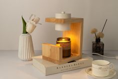 a table with a candle, cup and saucer on it next to a book