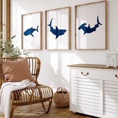 three framed pictures hang on the wall above a wicker chair in a white room