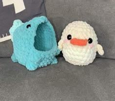 two crocheted stuffed animals sitting next to each other on a couch with pillows