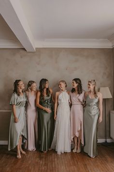 a group of women standing next to each other on a hard wood floor in front of a wall