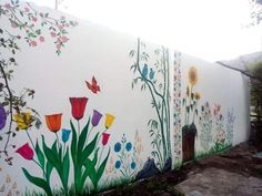 a white wall with flowers painted on it and butterflies flying over the flowerbeds