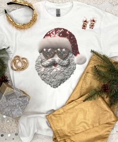 Introducing our Faux Sequin Santa Graphic Shirt, the perfect addition to your festive wardrobe this holiday season. This eye-catching shirt features a stunning faux sequin Santa face design that is sure to make you the life of the Christmas party. The beauty of this shirt lies in its clever use of faux sequins(these are not real sequins, they are grapic sequins). Our faux sequin design is not shiny/sparkly. This is a printed graphic design that is meant to give the look of sequins, it is not real sequins. It does look exactly like the photo as this is a printed graphic tee that shows the actual design printed on the tee.
Our Christmas shirt boasts a jolly Santa Claus graphic that captures the spirit of the season, making it an ideal choice for spreading joy and merriment. Whether you're lo Fall Party T-shirt With Sequins, Festive Glitter Tops For Party Season, Glamorous Festive Holiday Tops, Glamorous Holiday Festive Tops, Glamorous Christmas Sequin Tops, Christmas Party T-shirt With Graphic Print, Christmas Sequin Top For Festive Occasions, Holiday Sequin Top For Festive Occasions, Holiday Party T-shirt With Crew Neck