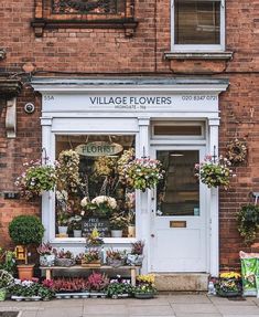 a flower shop with lots of flowers in front of the door and on the sidewalk