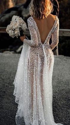 the back of a woman wearing a wedding dress with long sleeves and sequins