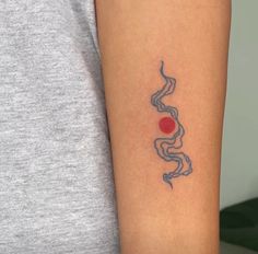 a woman's arm with a tattoo on it that has a red dot in the middle