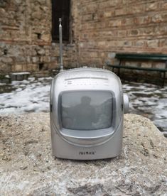 an old tv sitting on top of a rock