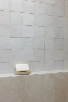 a white toilet sitting on top of a tiled wall