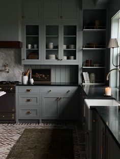 a kitchen with gray cabinets and marble counter tops, along with an area rug on the floor