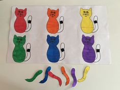 paper cut out of different colored cats on a white table with scissors and tape to make them look like they are looking at the same cat