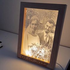 an illuminated photo frame with a bride and groom in the background on a white table