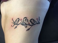 a woman's thigh with three birds sitting on branches tattooing her lower leg