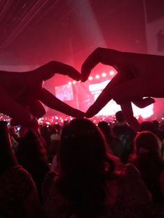 two hands making a heart shape at a concert