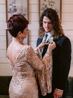 a man in a tuxedo helping a woman put on her wedding dress with a boutonniere