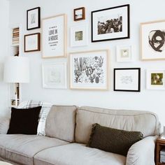 a living room filled with lots of framed pictures on the wall and a couch in front of it