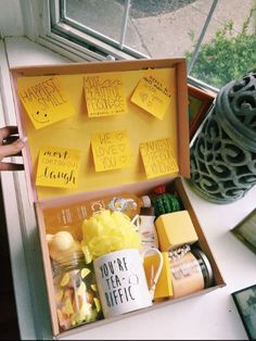 an open box with yellow sticky notes and other items in it sitting on a window sill