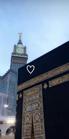 the ka'bah is decorated with intricate gold and black decorations in front of a large clock tower