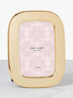 a pink and gold frame with the words kate spade on it