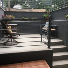 an outdoor patio area with stairs and table on the left, potted plants on the right