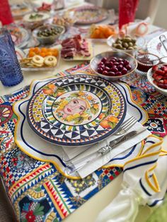 a table with plates and bowls of food on it, along with other items such as fruit