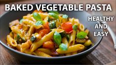 a bowl filled with pasta and vegetables on top of a wooden table