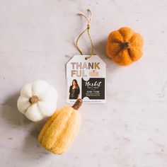 two small white pumpkins sitting next to each other on a marble surface with a tag that says, thank you